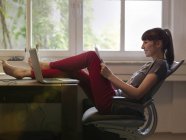 Femme avec les pieds sur le bureau papier de lecture — Photo de stock