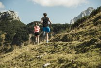 Austria, Tirol, Valle de Tannheim, pareja joven corriendo en las montañas - foto de stock