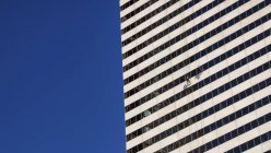 EE.UU., Illinois, Chicago, dos limpiadores de ventanas colgando en la fachada del rascacielos - foto de stock