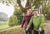 Senior man and adult grandson walking in park — Stock Photo