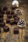 Primo piano di domino al cioccolato e coni di abete su legno — Foto stock