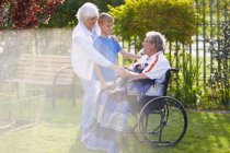 Oma und Enkel mit Opa im Rollstuhl auf Rasen — Stockfoto