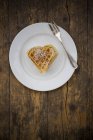 Dish of heart shaped waffles sprinkled with icing sugar on dark wood — Stock Photo