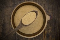 Wooden spoon and bowl of organic amaranth on dark wood — Stock Photo