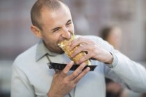 Portrait of businessman eating a sandwich at lunchtime — Stock Photo