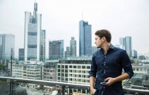 Німеччина, Гессен, Франкфурт, молода людина з його смартфон стоячи перед на skyline — стокове фото