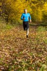 Uomo che corre nella foresta autunnale — Foto stock