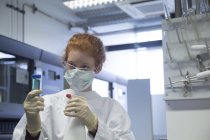 Femme scientifique naturelle avec masque désinfectant un test en laboratoire de biochimie — Photo de stock