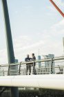Два бізнесмени стоять на мосту і розмовляють — стокове фото