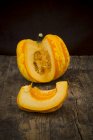 Sliced Chameleon pumpkin on dark wood — Stock Photo
