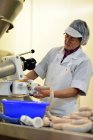 Donna che lavora alla produzione di salsicce in una macelleria — Foto stock