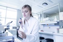 Giovane scienziata naturale donna che tinge uno scivolo per il microscopio leggero al laboratorio di microbiologia — Foto stock