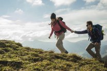 Австрия, Тироль, Таннхаймер Таль, молодая пара, идущая рука об руку на альпийском лугу — стоковое фото