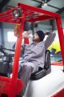 Worker on forklift having a break drinking water — Stock Photo