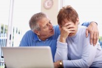 Uomo anziano consolante piangendo moglie al computer portatile — Foto stock
