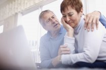 Uomo anziano consolante piangendo moglie al computer portatile — Foto stock
