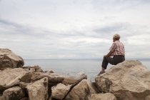 Словенія, Піран, жінка, сидячи на скелі на берегову лінію дивлячись обрію — стокове фото