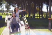 Woman with man in wheelchair and dog in park — Stock Photo