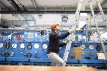 Joven técnico subiendo una escalera en la sala industrial - foto de stock