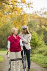 Senior woman and her adult granddaughter walking together in autumnal park — Stock Photo