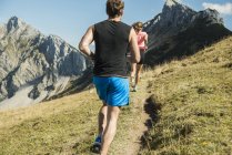 Austria, Tirol, Valle de Tannheim, pareja joven corriendo en las montañas - foto de stock