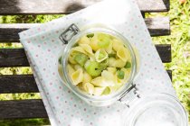 Preserving jar of noodle salad with avocado, peas and celery on cloth — Stock Photo