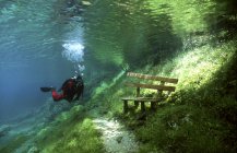 Дайвер перед скамейкой в парке под водой — стоковое фото