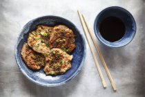 Japanese buckwheat pancakes with tofu and vegetable, chopsticks and bowl of soy sauce — Stock Photo
