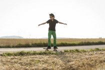 Ragazzi in piedi sul suo skateboard di fronte a un campo di stoppie — Foto stock