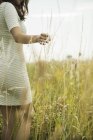Ritratto di giovane donna in piedi su un prato fiorito, vista parziale — Foto stock