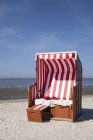 Germany, Lower Saxony, Dornum, Nessmersiel, red and white hooded beach chair — Stock Photo
