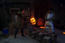Германия, Мюнхен, Литейный рабочий, заливающий горячий металл в литье — стоковое фото