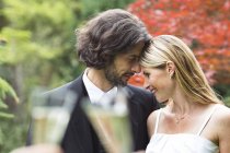 Felice sposa e sposo in giardino appoggiati l'uno all'altro — Foto stock