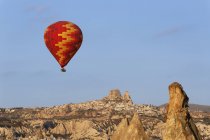 Turquía, Capadocia, globo aerostático flotando frente al pueblo de Uchisar en el Parque Nacional Goereme - foto de stock