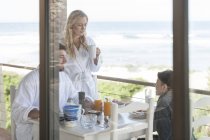 Famille sur le patio de la maison de plage manger le petit déjeuner — Photo de stock