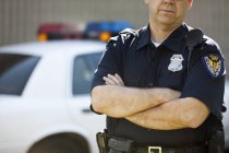 Policía serio americano de pie en coche - foto de stock