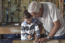 Nonno e nipote lavorano con il legno in un garage — Foto stock