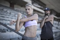 Portrait of sportswoman doing stretching exercies on grandstand of a stadium — Stock Photo