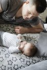 Jovem pai deitado no sofá olhando para o bebê — Fotografia de Stock