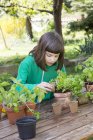 Little girl potting parsley on wooden table in the garden — Stock Photo