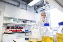 Giovane scienziata che lavora presso il laboratorio biologico cercando una bottiglia — Foto stock