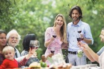 Couple tenant des verres de vin rouge lors d'une garden party — Photo de stock