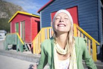 Happy young woman in front of colorful beach huts — Stock Photo