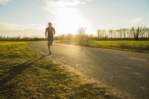 Young man jogging on rural road — Stock Photo