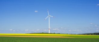 Alemanha, Tomerdingen, turbina eólica no campo de colza de floração amarela — Fotografia de Stock