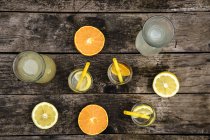 Графики и стаканы домашнего лимонада и апельсина на темной древесине — стоковое фото