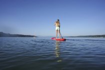 Giovane donna in piedi su stand up paddle board al lago Starnberg, vista posteriore — Foto stock