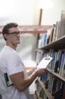 Young caucasian student looking for books in a library — Stock Photo