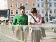Junges Paar läuft mit Handy auf der Straße — Stockfoto