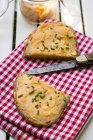 Дві половинки скибочку хліба з obazda посипати зелений лук, тканини, ніж і збереження jar на стіл — стокове фото